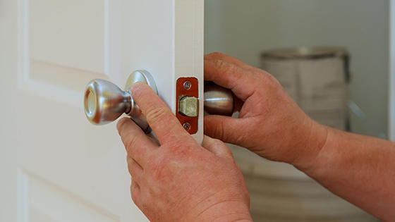 Closeup of a professional locksmith installing or repairing a new deadbolt lock